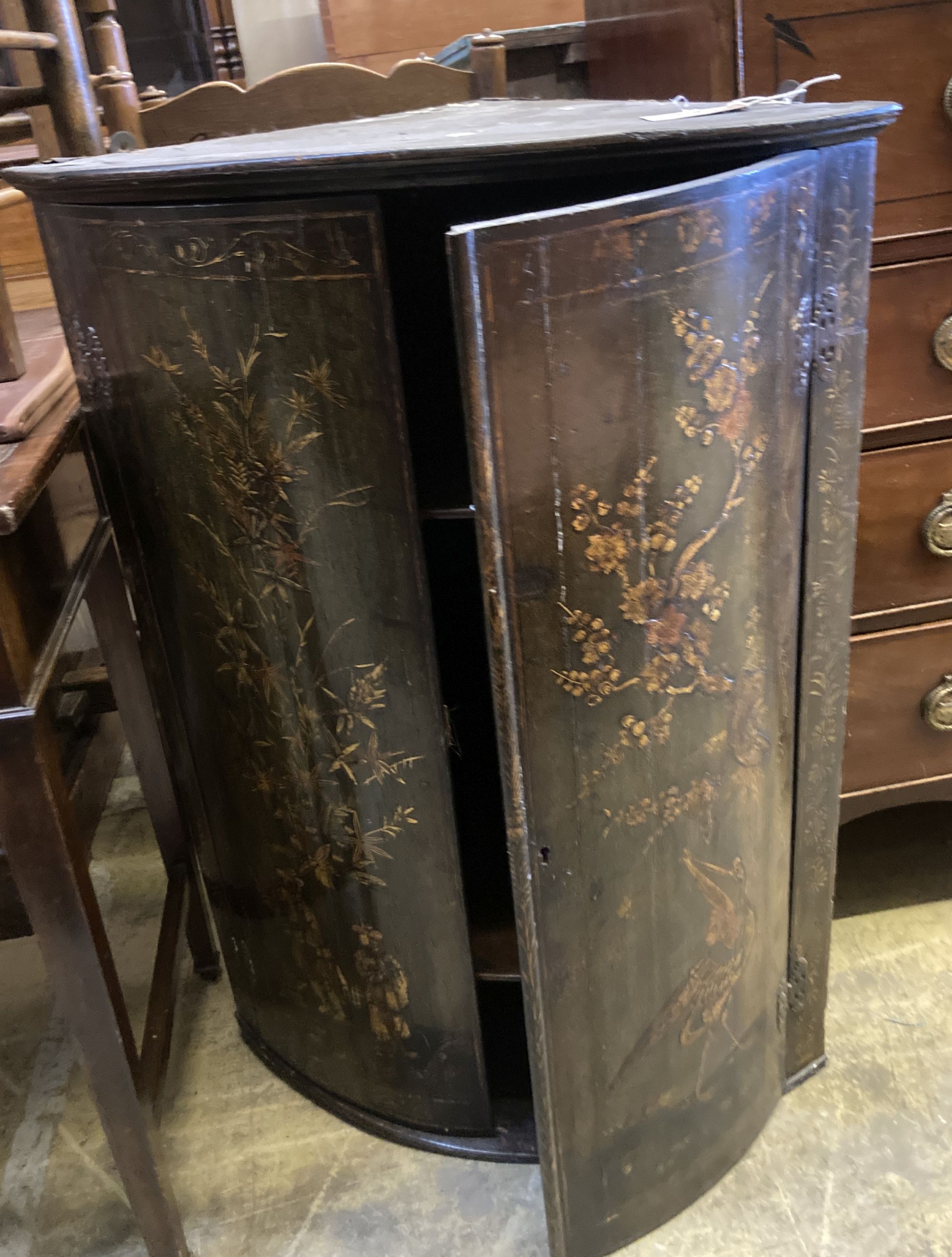 An 18th century chinoiserie lacquered bow front hanging corner cupboard, on later oak stand, width 66cm, depth 45cm, height 95cm